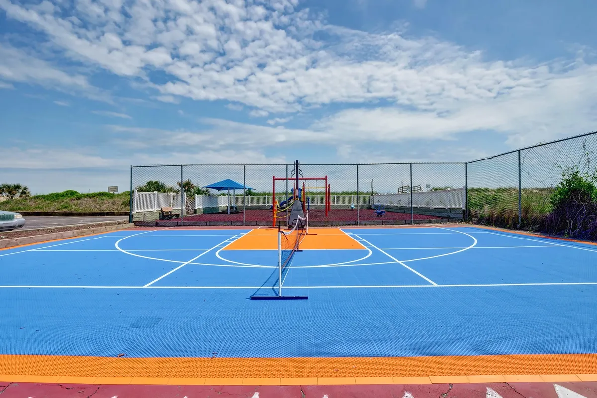 An outdoor multi-sport court with a colorful playing surface and net, suitable for basketball, tennis, or pickleball. The setting is lively and encourages active recreation and friendly competition among guests or families.