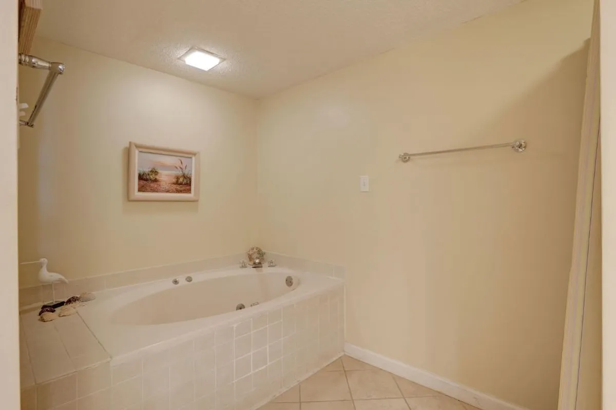 A tranquil ensuite bathroom with a large jacuzzi soaking tub, framed artwork, and a towel rack, evoking a spa-like atmosphere designed for relaxing baths and quiet moments of self-care.